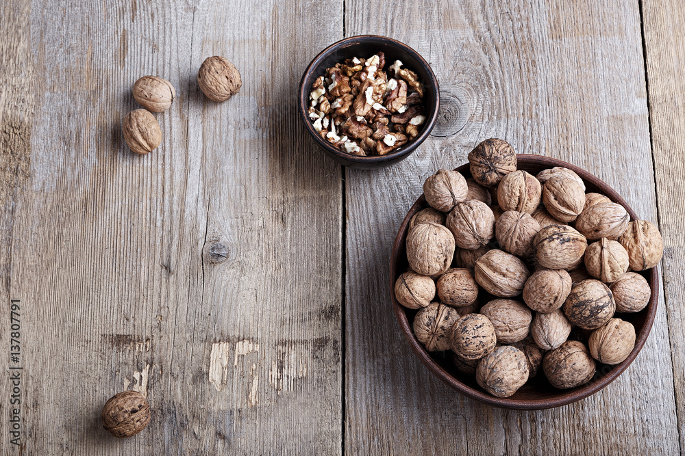 walnuts in a bowl on a wooden background walnuts in a bowl on a wooden background