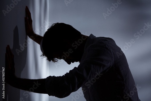 Man leaning hands against wall photo