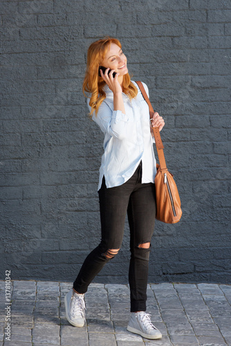 cheerful woman talking on mobile phone with bag