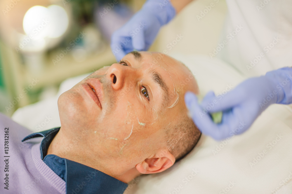 Relaxed man having a face massage and a peeling treatment Relaxed man having a face massage and a peeling treatment