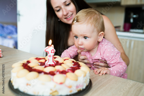 Mother with her cute daughter and birthday cake with candle