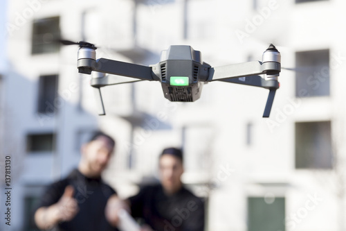 young guys are flying a drone with remote control outdoor