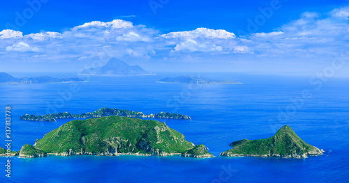 Beautiful summertime panoramic seascape. View of the cliff into the crystal clear azure sea bay and distant islands.