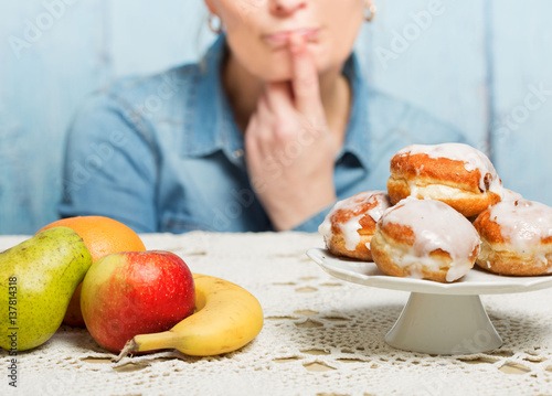 Woman choosing between fruit and sweets