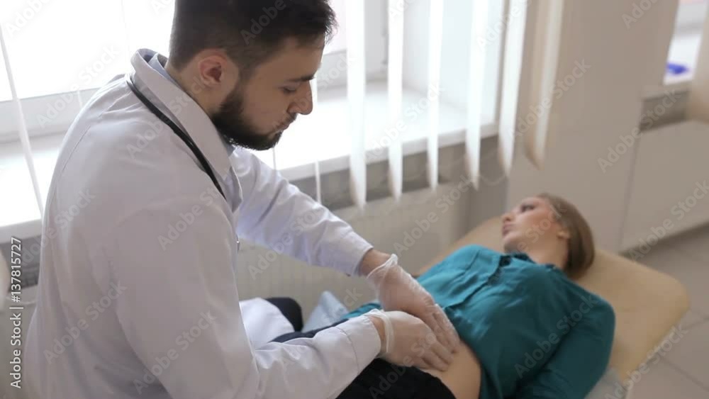 Doctor palpates the abdomen of young girl Doctor palpates the abdomen of young girl