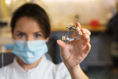 Dental technician presenting dental prosthesis in lab