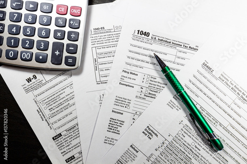 1040 and W-9 Forms with pen and calculator photo