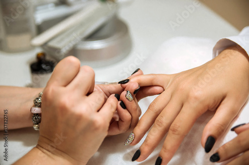 Manicure process in beauty salon  close up. Black nails