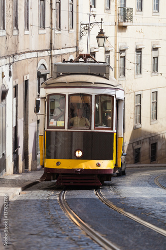 Vintage yellow tramway in Lisbon, Portugal. Bright tram on neutral background building. Tram edit up