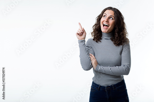 Pretty young woman with casual wear pointing up.