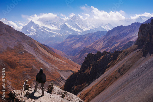 Nepal mountain landscape. Man, trekker, stand facing Annapurna Chain on the edge of the cliff at the High Camp, 4900m, on the way to Thorung La Pass, Annapurna Circuit, Himalaya, Asia