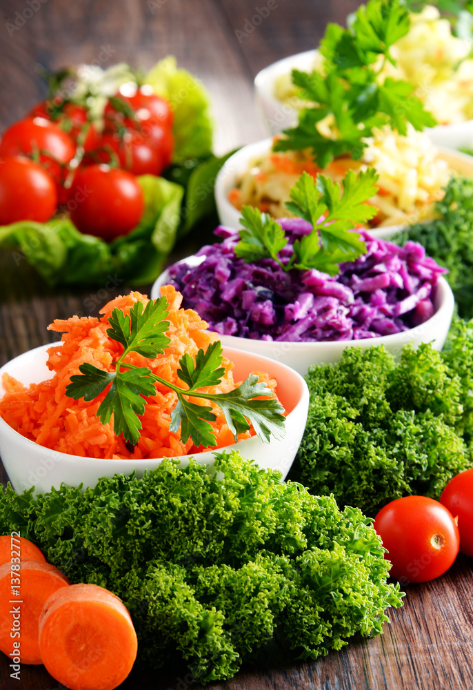 Composition with four vegetable salad bowls on wooden table Composition with four vegetable salad bowls on wooden table