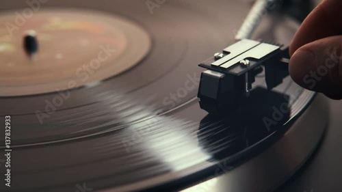 Gramophone and record to listen to. Included gramophone and torque plate close-up on a light background with bright lights. Hand puts needle on vinyl record