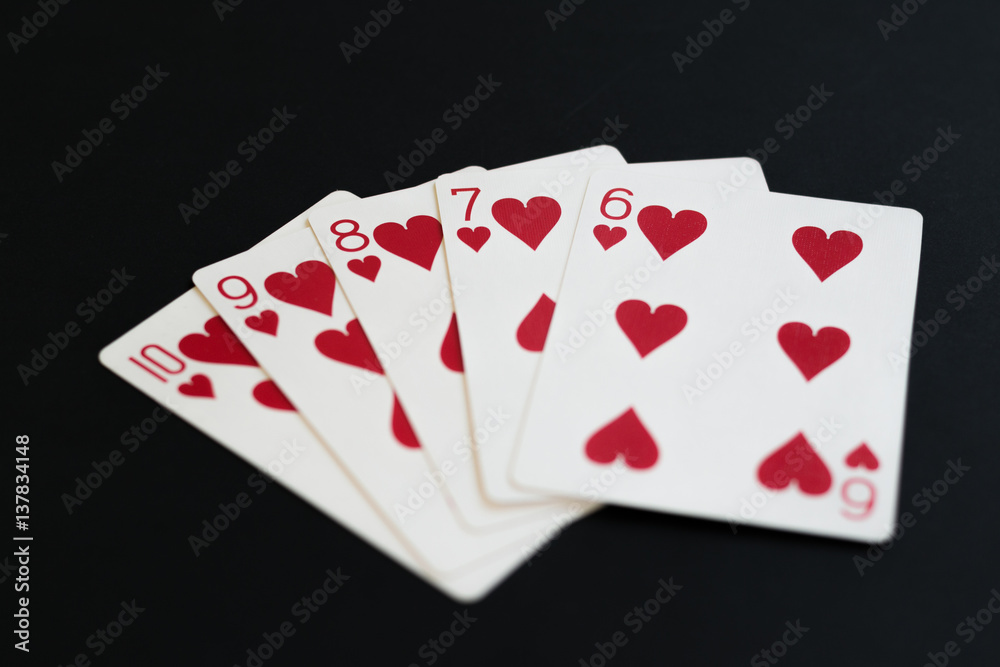 Straight Flush of hearts in poker cards game on a black background