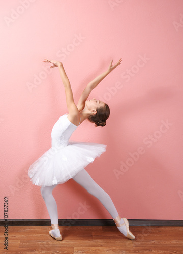 Young beautiful ballerina on wall background