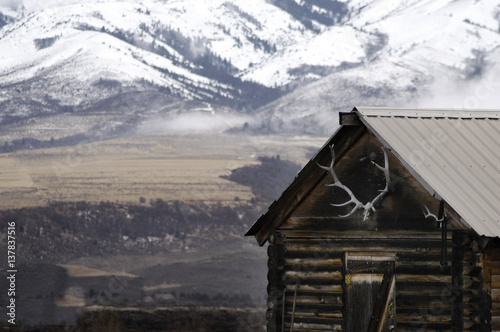Old Cabin with Snow Mountains and Elk Antlers