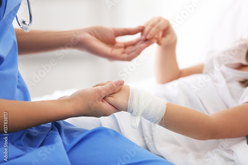 Closeup of doctor holding girl's hands in hospital