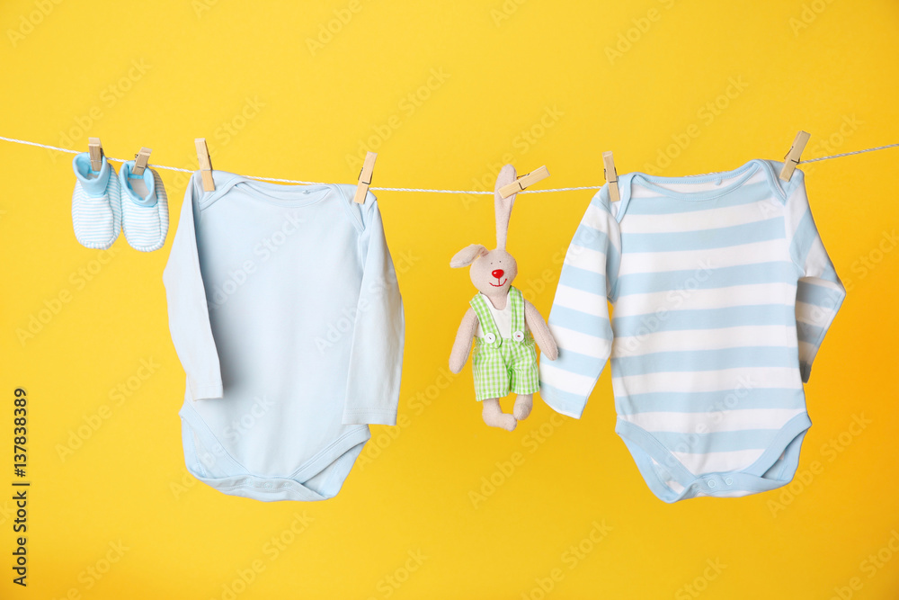 Εκτύπωση καμβά Clothesline with hanging baby clothes on yellow background