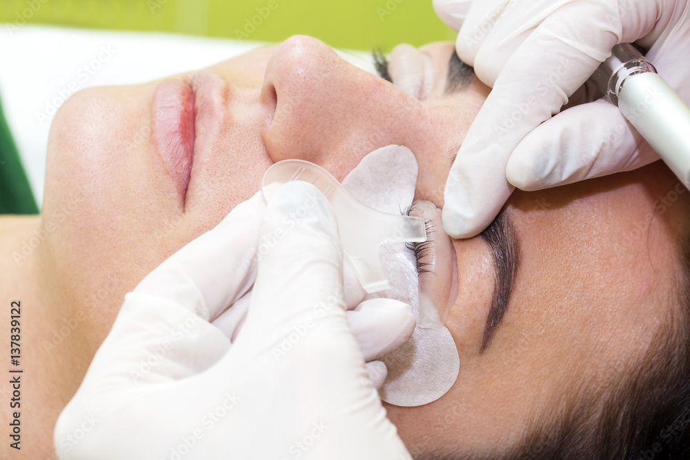 Woman on the procedure for eyelash extensions, eyelashes lamination Woman on the procedure for eyelash extensions, eyelashes lamination