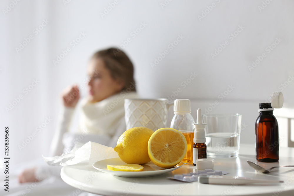 Medicines and lemons with blurred ill woman on background Medicines and lemons with blurred ill woman on background
