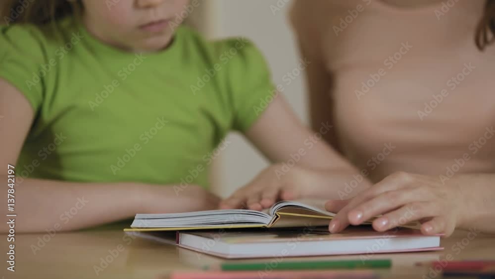 Mother and little daughter reading stories in book, enjoying leisure together Mother and little daughter reading stories in book, enjoying leisure together