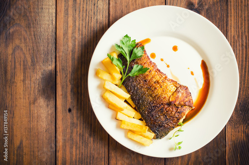 Fried fish steak with fries. Wooden background. Top view. Close-up