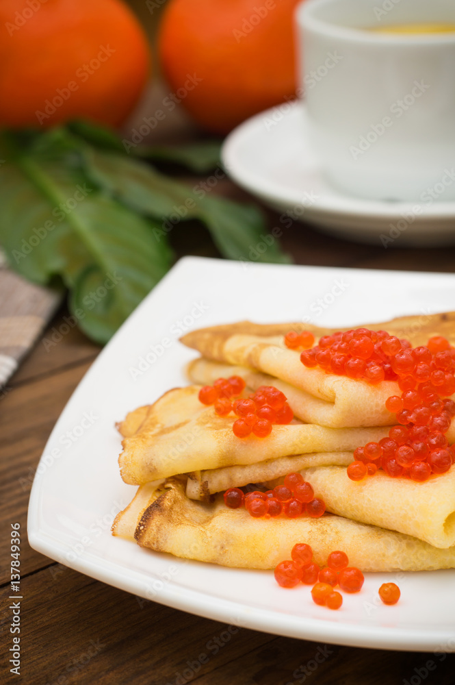 Pancakes with red caviar. Russian cuisine. Flat lay. Maslenitsa. Wooden background. Close-up