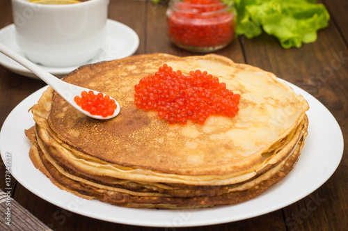 Pancakes with red caviar. Russian cuisine. Flat lay. Maslenitsa. Wooden background. Close-up