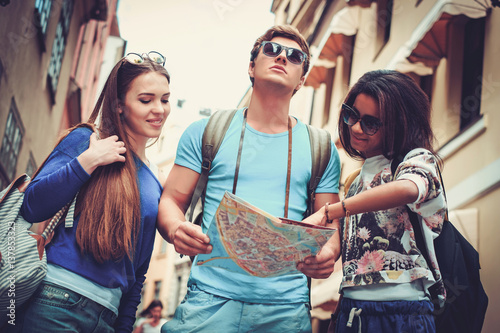 Multi ethnic friends tourists with map in old city photo