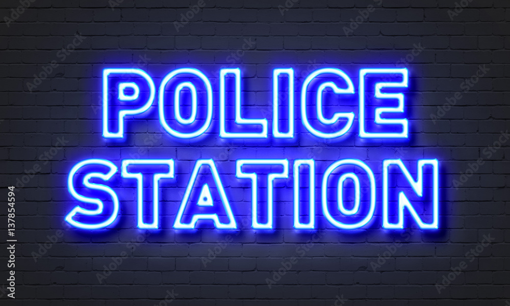 Police station neon sign on brick wall background.