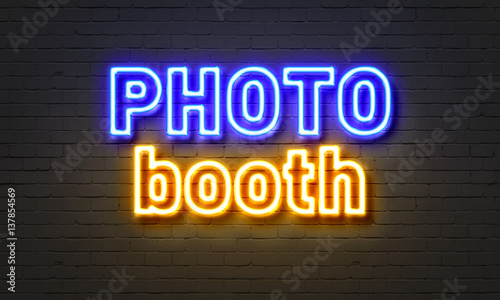Photo booth neon sign on brick wall background.