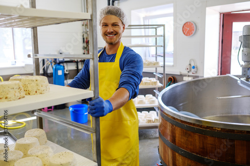 Obraz na płótnie Handsome cheesemaker making curd cheese in his factory
