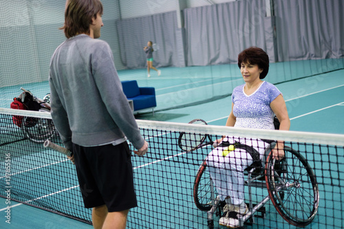 Disabled mature woman on wheelchair playing tennis with a coach © Nejron Photo