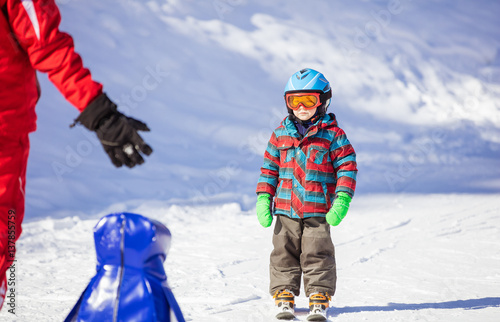 Young skier looking at ski instructor or parent while standing on mountain slope