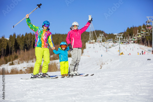 Cheerful family of three standing on ski slope