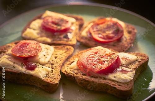 Melted cheese on toast with sliced tomato and herbs