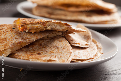 Crispy Quesadilla with Chicken and Sauce on white plate on dark wooden background horizontal shot