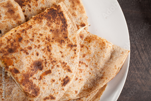 Crispy Quesadilla with Chicken and Sauce on white plate on dark wooden background above shot