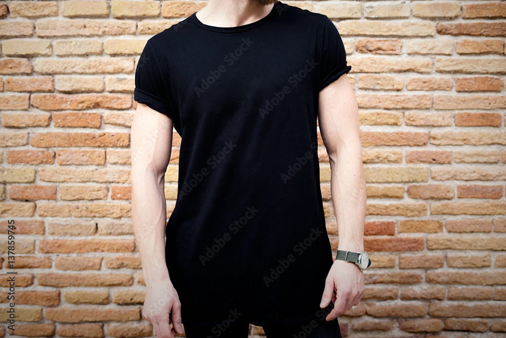 Closeup view of young muscular man wearing black tshirt and jeans posing outside. Empty brown grunge brick wall on the background. Hotizontal mockup. Closeup view of young muscular man wearing black tshirt and jeans posing outside. Empty brown grunge brick wall on the background. Hotizontal mockup.