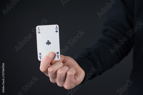 Mann hält ein Ass in der Hand auf schwarzem Hintergrund