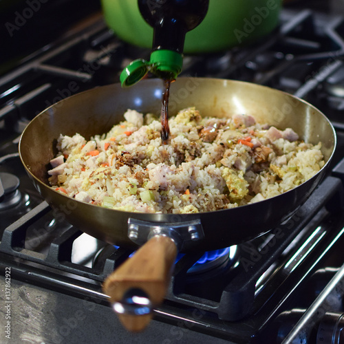 Wallpaper Mural adding soy sauce to fried rice in wok over gas flame stove Torontodigital.ca