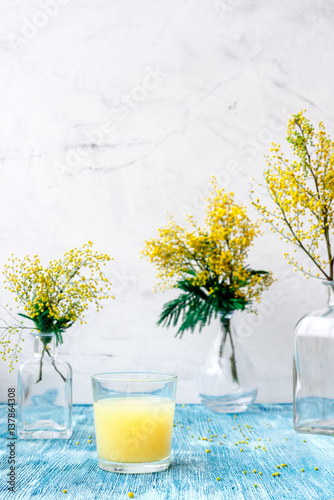 mimosa in glass vase on blue table close up