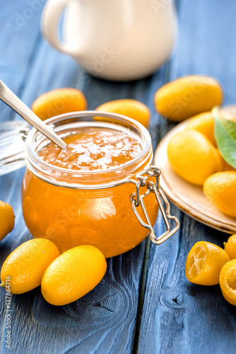 kumquat on plate and jam in jar at wooden table