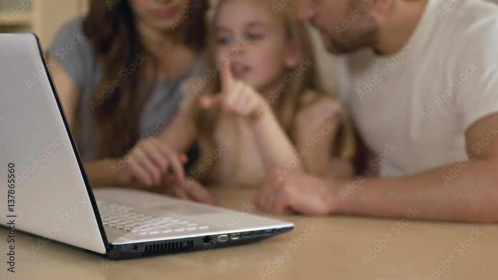 Family using laptop for shopping, booking tickets online or viewing pictures Family using laptop for shopping, booking tickets online or viewing pictures