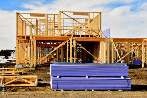 Two story wood frame residential building under construction with material in foreground. photo