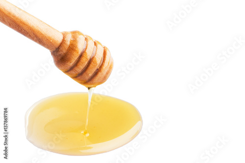 Honey dripping from a wooden honey dipper on isolate white background. ready to use with clipping path.