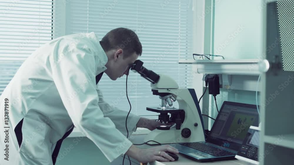 Technologist or pathologist using a microscope in a medical laboratory during a diagnostic test or while doing scientific research Technologist or pathologist using a microscope in a medical laboratory during a diagnostic test or while doing scientific research