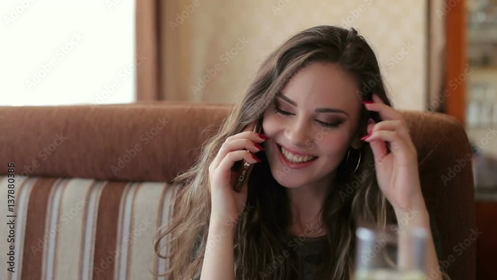 Attractive female with cute smile talking on the phone while rest in cafe. Attractive female with cute smile talking on the phone while rest in cafe.