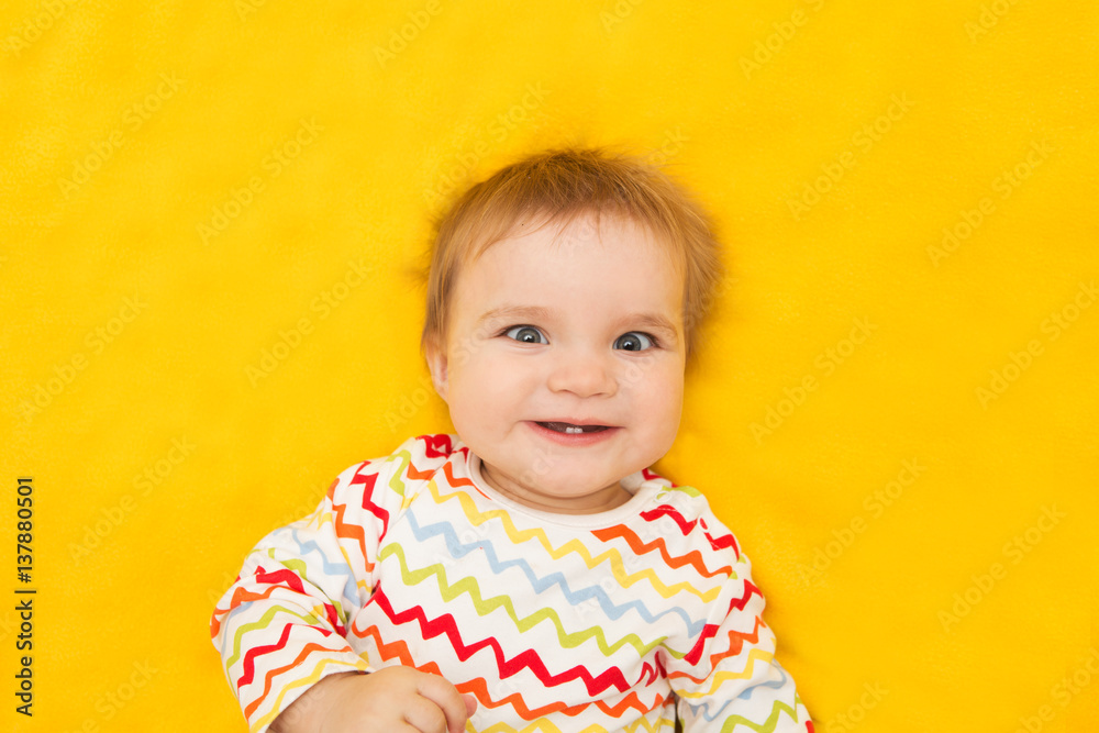 Portrait cheerful baby on a yellow background Portrait cheerful baby on a yellow background