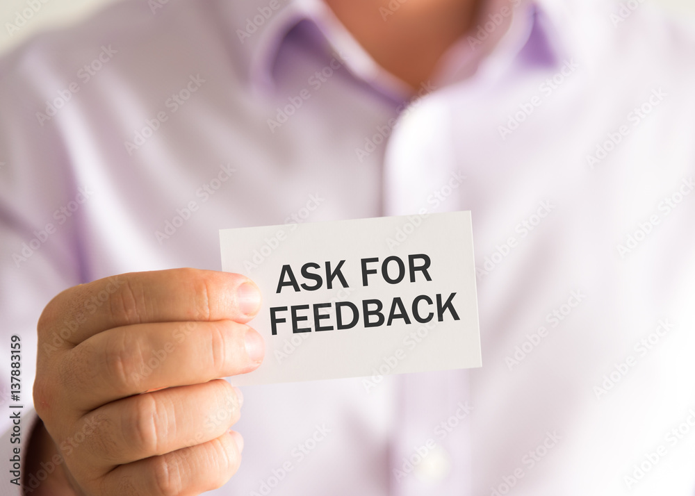 Businessman holding a card with text ASK FOR FEEDBACK Businessman holding a card with text ASK FOR FEEDBACK